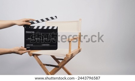 Director chair in ivory color and hand is hold clapper board on white background