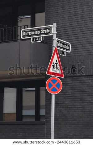 Warning and directional road sign in front of black bricked building