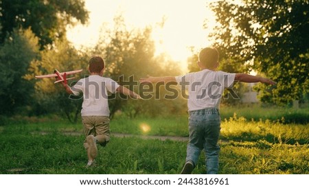 Boys, children are running with plane in their hands. Two children play with toy airplane in park in summer. Children boys play with toy airplane outdoor. Child dream is to fly, travel. Dream of Royalty-Free Stock Photo #2443816961