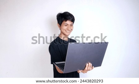 Excited young Asian man with gestures holding a laptop on an isolated white background