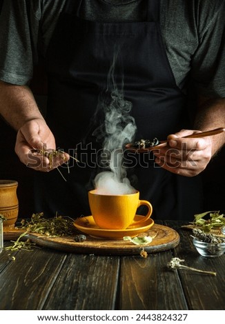 Herbalist prepares tea from medicinal plants rose hips and chamomile on the home table. Low key concept of traditional medicine. Royalty-Free Stock Photo #2443824327