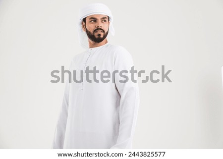 Middle eastern man with traditional emirates clothing posing in a photographic studio - Concepts about lifestyle, happiness and family relationship in the UAE Royalty-Free Stock Photo #2443825577