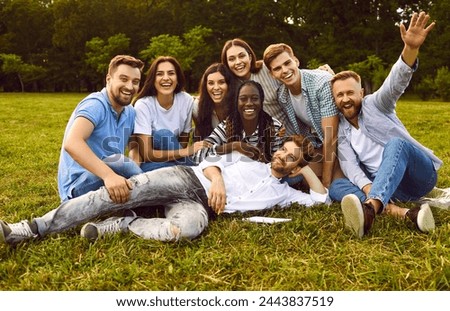 Happy diverse university students and friends having fun together. Team of cheerful muliracial young people posing for group photo portrait on green grass in park in summer