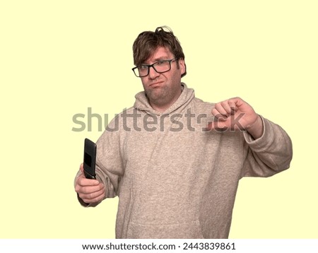 Man Looking Disgusted While Holding A Phone And Showing A Thumbs Down On Papaya Whip Background