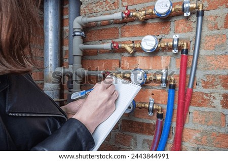 Checking the readout on a water meter. Household water consumption, cost of water symbolic image. Royalty-Free Stock Photo #2443844991