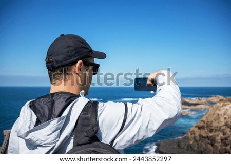 a man takes pictures of nature on his phone. guy takes pictures of the sea