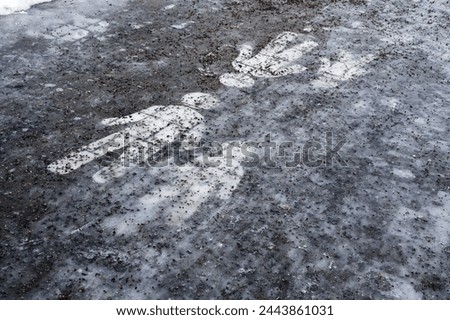  Ice covered sidewalk with a pedestrian path sign sprinkled with granite chips 