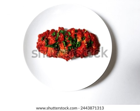 close-up of crispy and soft tasty katsu tofu sprinkled with celery leaves on a white plate isolated on a white background.