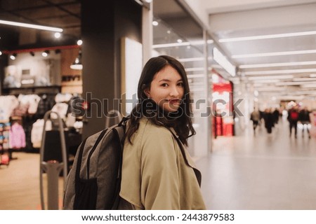 Beautiful teen girl holding shopping bags and smiling while doing shopping in mall.