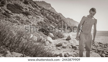 Black and white picture of a young traveler hiker with natural coastal landscapes on Kos Island in Greece with mountains cliffs rocks turquoise blue beaches and waves.