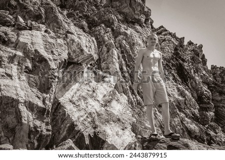Black and white picture of a young traveler hiker with natural coastal landscapes on Kos Island in Greece with mountains cliffs rocks turquoise blue beaches and waves.