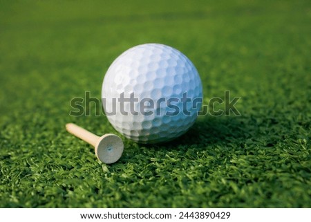 A picture of a golf ball lying on the grass next to the tee, not ready for playing.
