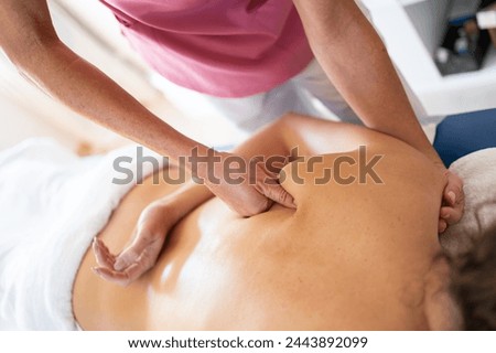 Crop female osteopathic therapist massaging back of patient Royalty-Free Stock Photo #2443892099