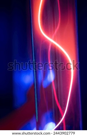 A purple and blue glowing tube with a red line running through it. The tube is lit up and he is a neon light Royalty-Free Stock Photo #2443902779