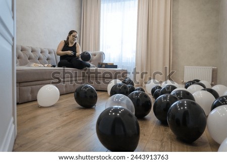 A young woman inflates balloons with a hand-held air pump, the concept of inflating air into a balloon, a children's game, toys and equipment for fun games or party preparation. Royalty-Free Stock Photo #2443913763