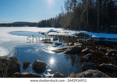 The spring sun is reflected in the calm water of a lake that has a small ice-free surface near the inlet.
Picture from vasternorrland  Sweden.