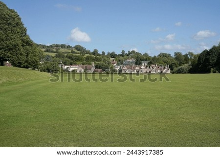 Scenic view of a beautiful spacious lush green playing field lawn in a town park with a bright blue sky above