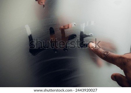 A hand tracing 'LIFE' on a foggy mirror, pondering existence
