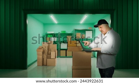 Man with laptop in storage unit. Male rents warehouse room. Guy near gate in place for safekeeping. Businessman picks up goods from warehouse. Gate to storage unit is open. Man leaves storage unit Royalty-Free Stock Photo #2443922631