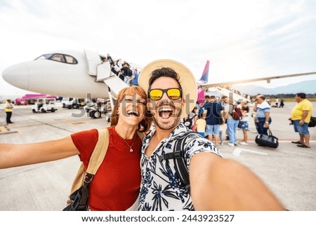 Happy couple of tourists boarding on a plane at the airport - Happy man and woman having happy summer vacation together - Transportation and holidays concept