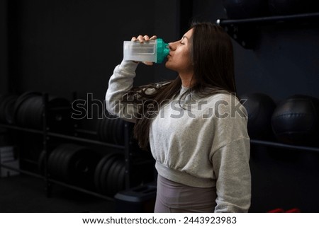 Close up of a woman taking protein from her shaker at the gym