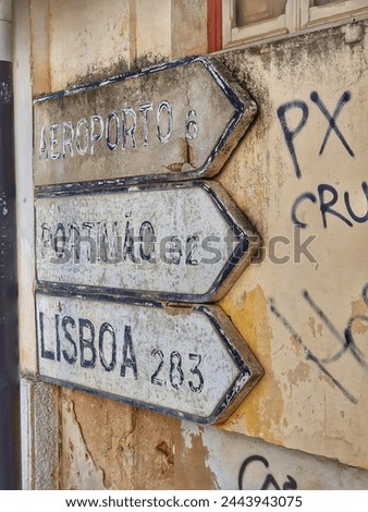 Dilapidated, used Road Sign Pointing to Aeroporto, Portimao, Lisboa. Attached to a yellow House Wall in Faro, Portugal.