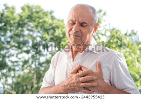 senior, mature man 60-65 years old holds to heart, sudden chest pain, close up male face with facial expression suffering, Ischemic heart disease, Arterial hypertension, Myocarditis or Arrhythmia Royalty-Free Stock Photo #2443955425