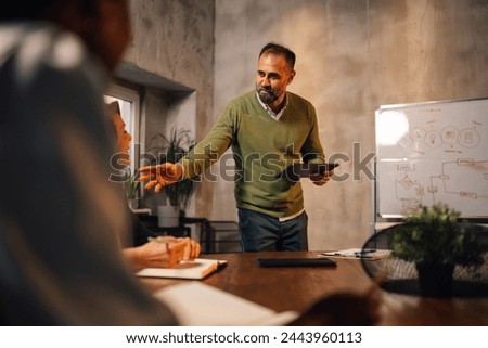Mature businessman presenting and pitching new innovative business ideas and strategies at conference room in front of investors. Manager presenting business strategy on whiteboard at boardroom.