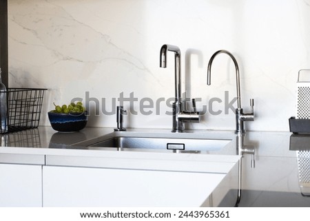 Kitchen brass utensils, chef accessories. Hanging modern kitchen with white marble wall and stone tabletop.