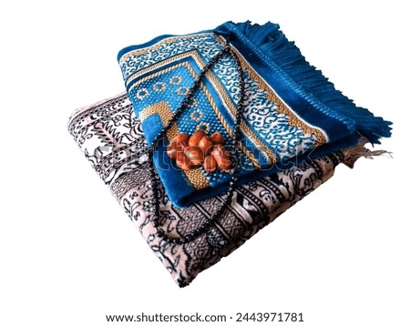 Folded Muslim prayer mat used to pay with tasbih and khajoor (Dates) on white background Royalty-Free Stock Photo #2443971781