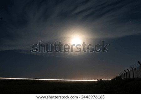long exposure photography of car on night road with moon simulating an eye with clouds
