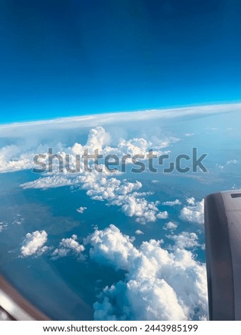 A view from the airplane window reveals a vast expanse of blue sky adorned with fluffy white clouds, evoking a sense of serenity and freedom.