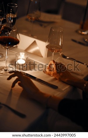 people hold glasses of white and red wine in a night restaurant, celebrating.