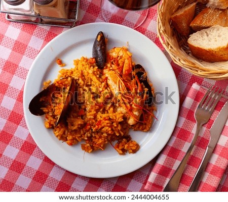 Appetizing racy seafood paella with mussels and prawns.Traditional Valencian cuisine Royalty-Free Stock Photo #2444004655