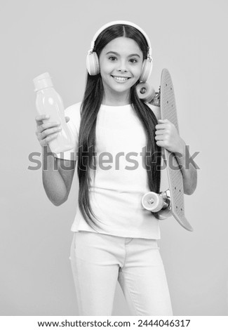 Happy teenager portrait. Fashion teenage lifestyle, beautiful teen girl with skateboard and headphones isolated on studio background. Smiling girl.