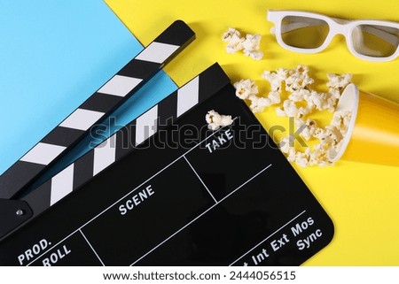 Clapperboard, popcorn and 3D glasses on color background, flat lay
