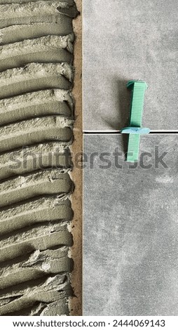 Tile glue with a toothed spatula. Adhesive background. Cement wall vertical photo Royalty-Free Stock Photo #2444069143