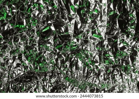 Glaring surface. Crumpled aluminum foil. Crumpled background. Colored glitter. Soft focus
