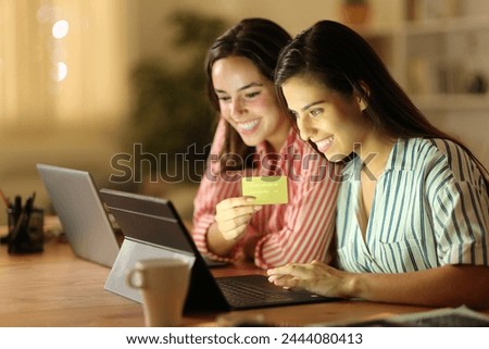 Two tele workers buying online with tablet and credit card at home in the night Royalty-Free Stock Photo #2444080413