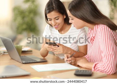 Two tele workers taking photo of contract sitting at home Royalty-Free Stock Photo #2444080417