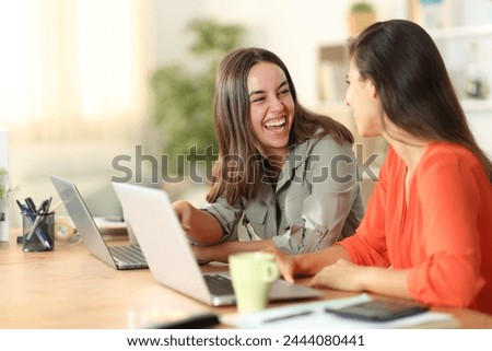 Two tele workers talking and laughing wasting time at home Royalty-Free Stock Photo #2444080441