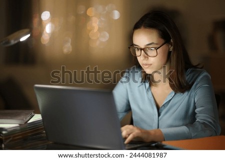 Tele worker working with eyeglasses using laptop in the night at home office Royalty-Free Stock Photo #2444081987