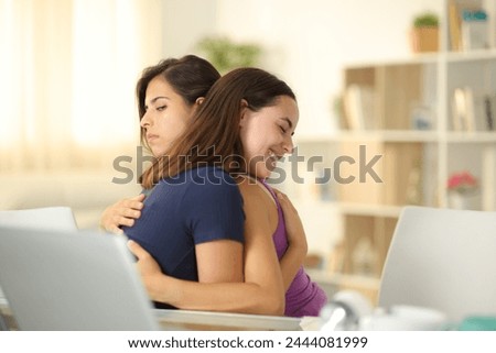 False woman hugging a cheated friend at home Royalty-Free Stock Photo #2444081999