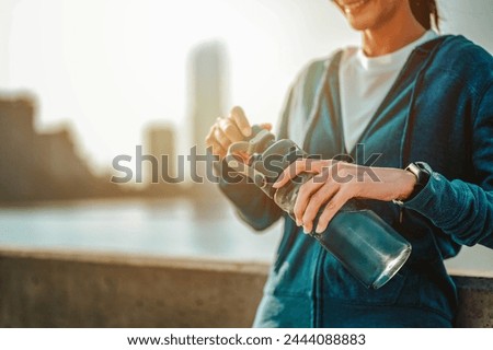 exercising, jogging, determination, workout, run, runner, vitality, jogger, relaxation, healthy. A woman is holding a water bottle and smiling. Concept of relaxation and enjoyment.