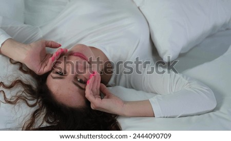 Young woman sleeping in bed. Portrait of a beautiful woman resting on a comfortable bed with pillows in white bedding in the bedroom in the morning. High quality image.