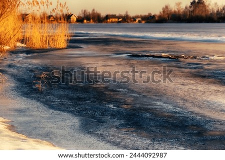 North-eastern European river after frosty winter. Porous ice began to melt, river is swollen, state of ice week before ice break (ice-boom). Aurora, sunrise colors on a spring moning Royalty-Free Stock Photo #2444092987