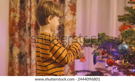 Happy child arranging decorations in the Christmas tree