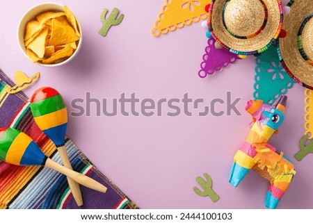 Celebratory Cinco de Mayo frame. Overhead picture highlighting festive accessories: sombrero, lama pinata, maracas, colorful serape, flag strands, bowl of nachos, lavender backdrop, with area for text