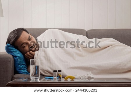 A sick young man lying on sofa while suffering from fever