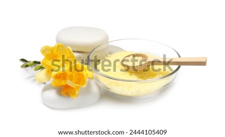 Yellow sea salt in bowl, flowers, spa stones and spoon isolated on white